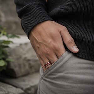 Man wearing a polished tungsten ruby wedding ring with vibrant red gemstone inlay.