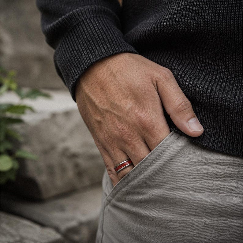 Man wearing a polished tungsten ruby wedding ring with vibrant red gemstone inlay.