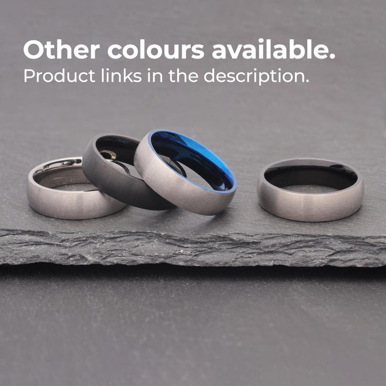 May include: Three different colored rings on a dark gray surface. The rings are all the same width and have a brushed finish. The rings are silver, black, and blue.