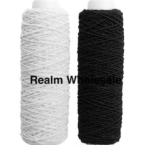May include: Two spools of yarn, one white and one black, are shown. The yarn is tightly wound around a white cylindrical base. The text "Realm Wholesale" is visible on the white spool.