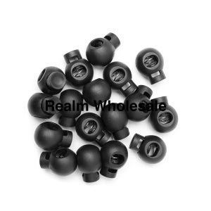 May include: A collection of black cord locks, or cord fasteners, on a white background. Each cord lock has a spring mechanism. The text "Realm Wholesale" is visible.