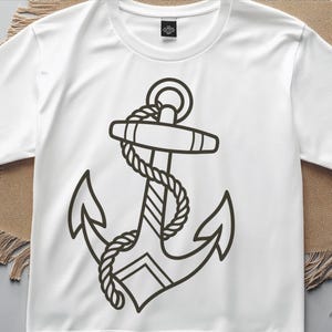 May include: White t-shirt featuring a black anchor design with rope detailing. The anchor graphic is centered on the shirt. The shirt has short sleeves and a crew neck. The design is a nautical theme.