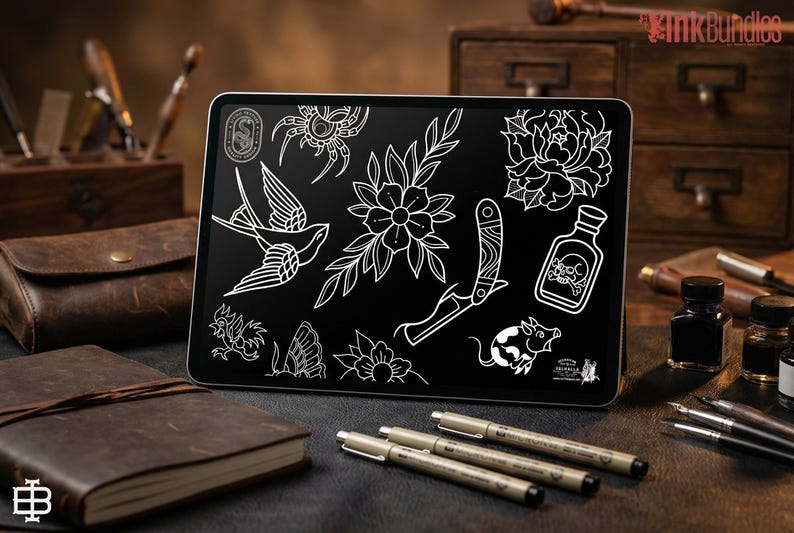 May include: A digital tablet displays a collection of white line art tattoo designs on a black background. The designs include a swallow, flowers, a knife, and a skull bottle. The tablet is surrounded by leather-bound notebooks, pens, and ink bottles.