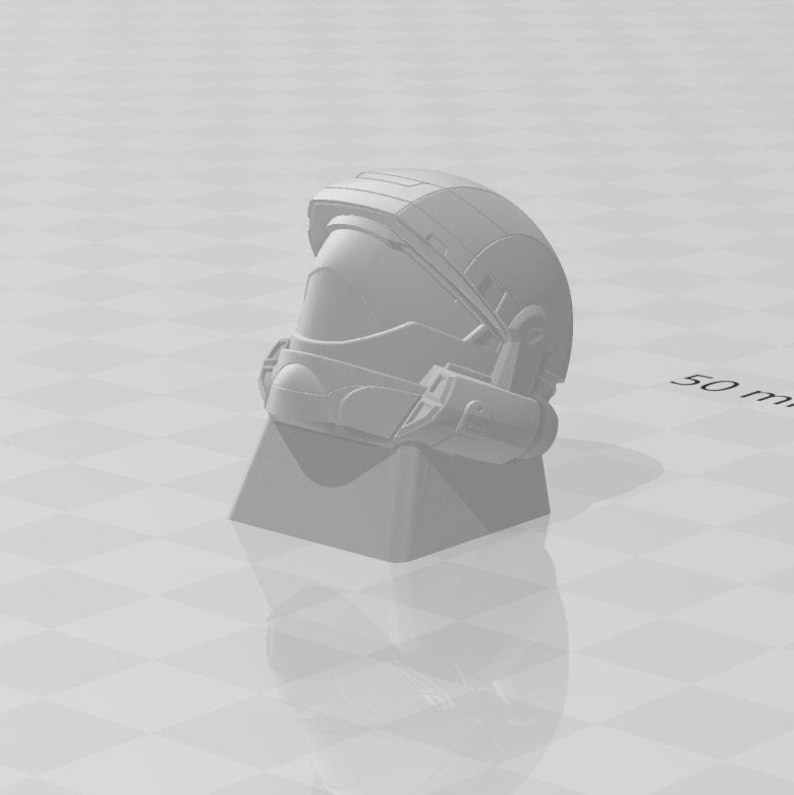 K&ouml;nnte beinhalten: Ein 3D-gedrucktes Modell eines Helms aus grauem Kunststoff mit Visier und strukturierter Oberfl&auml;che. Der Helm steht auf einem grauen Sockel.