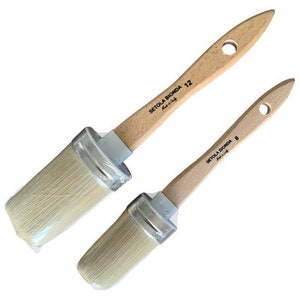 May include: Two angled paint brushes with light-colored bristles and wooden handles. The handles have a hole for hanging and the text "SETOLA BIONDA Made in Italy". One brush is labeled "12" and the other "8".