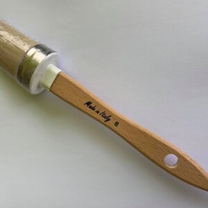May include: A round paint brush with a light wood handle. The brush head is wrapped in clear plastic. The handle has the text "Made in Italy" and the number "8" printed on it.