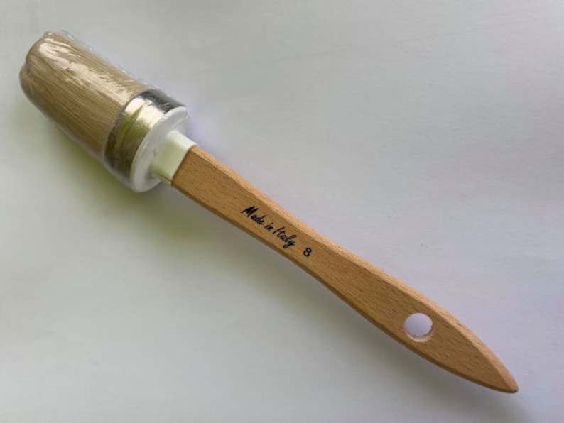 May include: A round paint brush with a light wood handle. The brush head is wrapped in clear plastic. The handle has the text "Made in Italy" and the number "8" printed on it.