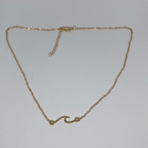 May include: A gold chain necklace with a wave pendant.