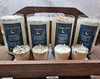May include: Four glass candle jars with labels that read "I Am Grounded", "I Release", "I Begin Anew", and "I Manifest". Each jar contains a white candle with herbs and essential oils. There are also four smaller candles in the image.