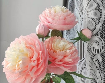 May include: A bouquet of three pink paper peonies with white centers and two closed buds. The peonies are arranged with green paper leaves.