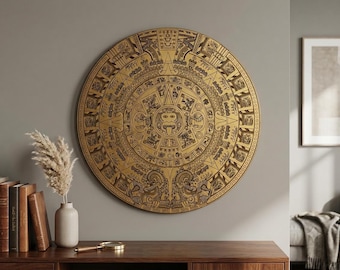May include: A large circular wall plaque featuring a detailed gold-colored Aztec calendar design with intricate black engravings. The artwork displays a central face surrounded by concentric rings of symbolic glyphs and figures on a metallic surface.