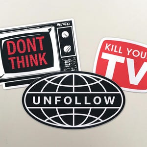 May include: A set of stickers with striking graphic designs. One shows a vintage TV with "DON'T THINK" in red. Another says "KILL YOUR TV" in white on red. The third is a black and white oval with "UNFOLLOW".