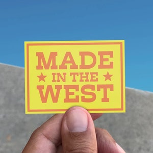 May include: A yellow card with a red border and the text "MADE IN THE WEST" in red letters with two red stars.
