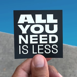 May include: A black card with white text that reads "ALL YOU NEED IS LESS".