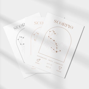 May include: A white card with the word "SCORPIO" in gold lettering. The card features a gold outline of the Scorpio constellation with stars inside. The card also includes the dates "OCT 23 - NOV 21", the symbol for Mars, and the word "WATER".