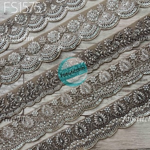 Könnte beinhalten: Nahaufnahme von vier Reihen Perlenbesatz mit gewellten Kanten. Der Besatz ist beige mit silbernen und schwarzen Perlen und Pailletten. Der Besatz ist versetzt angeordnet. Der Text "FS1575" ist in der oberen linken Ecke des Bildes sichtbar.