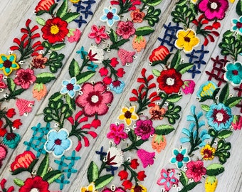 Peut inclure: Garniture de broderie florale multicolore sur un tissu blanc transparent. La garniture présente une variété de fleurs dans des tons de rouge, rose, jaune, bleu et vert.