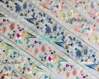 Peut inclure: Cinq galons en tissu beige avec des motifs floraux brodés colorés. Les galons présentent différentes couleurs, notamment le rose, le bleu, le vert, le jaune et le blanc.