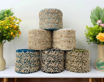 May include: Six spools of embroidered trim in various colors, including teal, gold, black, and green. The trim features a floral pattern with gold accents.