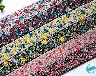 May include: A collection of seven embroidered ribbon trims featuring floral patterns in various colors, including pink, red, yellow, blue, and green. The ribbons are arranged in a staggered pattern, creating a visually appealing display.
