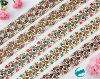 May include: Close-up of several decorative floral embroidered ribbons. Each ribbon features a repeating pattern of colorful flowers and leaves, with a sheer, light-colored backing. The ribbons are in various colors, including red, purple, and blue.