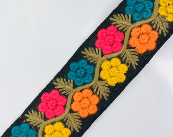 Peut inclure: Garniture en tissu noir avec des fleurs brodées colorées. Les fleurs sont dans des tons d'orange, jaune, rose et bleu.