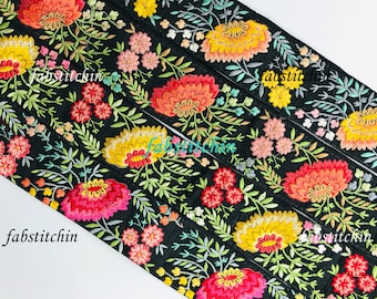 Peut inclure: Ruban en tissu noir avec des motifs floraux brodés colorés. Le ruban présente un motif répétitif de fleurs dans des tons de jaune, orange, rouge, rose et vert.