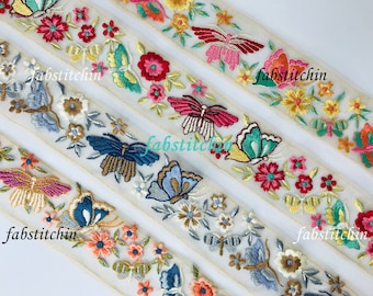 May include: A close-up of embroidered trim featuring colourful butterflies and flowers on a sheer white fabric. The trim is perfect for adding a touch of whimsy to clothing, accessories, and home decor projects.
