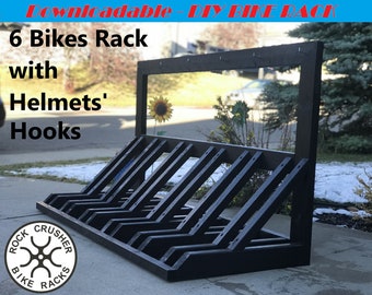 May include: A black wooden bike rack designed to hold six bikes, with a top section for helmets. The rack has a sturdy, angled design and includes the text "6 Bikes Rack with Helmets' Hooks" and "Rock Crusher Bike Racks".
