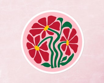 May include: A pink circle sticker with three red flowers with yellow centers and green stems and leaves.