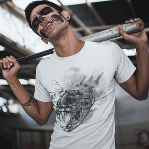 May include: A white t-shirt with a black and white graphic print of a skull with a watercolor effect. The skull has sharp teeth and is surrounded by black splatters.