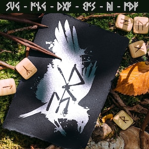 Könnte beinhalten: Eine schwarze Karte mit einem weißen Raben-Design und Runensymbolen, umgeben von Holzrunen und Blättern. Die Karte zeigt oben den Text "SVG - PNG - DXF - EPS - AI - PDF". Die Szene ist auf einem Moos- und Blätterbett angeordnet.