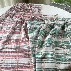 Peut inclure: Deux ensembles de rideaux en tissu à motif écossais. L'un présente des rayures rouges et blanches, tandis que l'autre a des rayures vertes et blanches. Les rideaux sont drapés sur une table blanche, mettant en valeur leur design et leur texture.