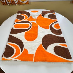Manta vintage de los años 60, con laterales cortados, estampado naranja y marrón, fondo blanco, remanente de vellón de los años sesenta, 183 cm de largo x 140 a 142 cm de ancho.