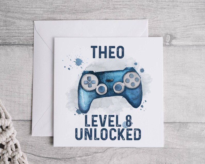 May include: A blue and white birthday card with a watercolor illustration of a video game controller. The card says "Theo Level 8 Unlocked".