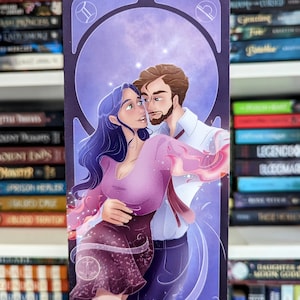 Puede incluir: Un marcapáginas ilustrado morado y azul con una pareja bailando bajo un cielo estrellado. El hombre lleva una camisa blanca y una corbata roja. La mujer lleva un vestido morado. El marcapáginas tiene el símbolo del zodíaco de Géminis en la parte superior.