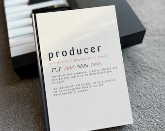 May include: A white card with the word "producer" in black text and a definition of the word in smaller black text. The definition includes the pronunciation of the word and two descriptions of what a producer does. The card is sitting on top of a black keyboard.