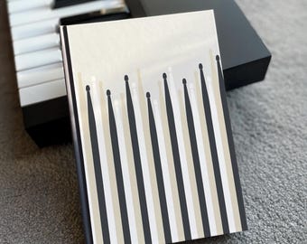 May include: A white notebook with a black and beige striped pattern. The notebook is closed and has a blank cover.