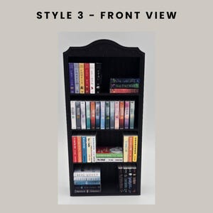 Puede incluir: Estanter&iacute;a negra en miniatura llena de libros coloridos. La estanter&iacute;a tiene una parte superior decorativa y varios estantes. El texto "STYLE 3 - FRONT VIEW" est&aacute; en la parte superior de la imagen.