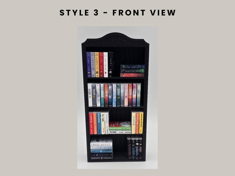 Puede incluir: Estanter&iacute;a negra en miniatura llena de libros coloridos. La estanter&iacute;a tiene una parte superior decorativa y varios estantes. El texto "STYLE 3 - FRONT VIEW" est&aacute; en la parte superior de la imagen.