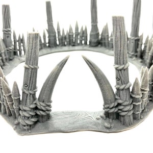May include: A gray 3D printed crown with a wooden base and two large horns. The crown is decorated with rope and spikes.