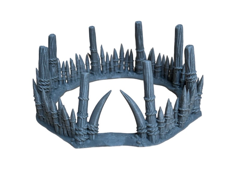 May include: A gray, 3D printed, circular, spiked fence with a gap in the front. The fence is made of wooden posts and spikes, and has a rope-like texture.