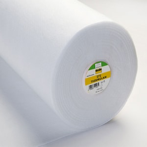 Può includere: Un rotolo bianco di tessuto termoadesivo 272 Thermolam. L'etichetta riporta "272 Thermolam 100% PES 90 cm x 25 m".