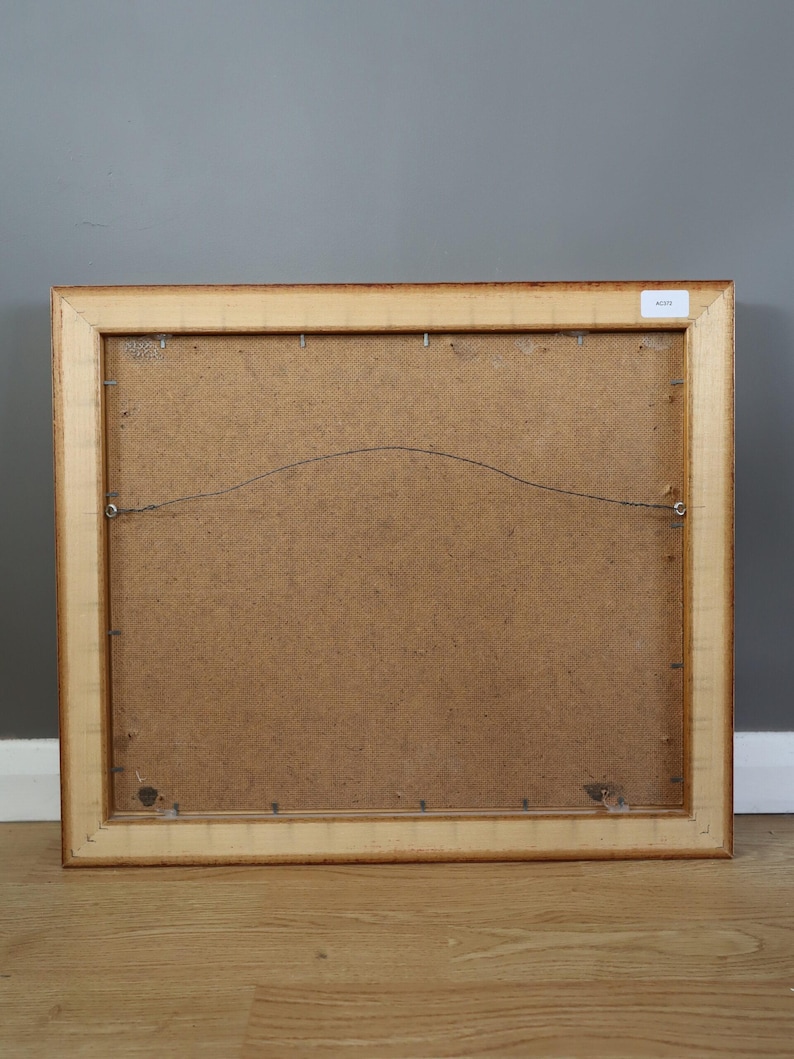 Pode incluir: Verso de uma obra de arte emoldurada com uma moldura de madeira castanha clara. A parte de tr&aacute;s da obra de arte &eacute; um material texturizado castanho claro. Um fio &eacute; esticado na parte de tr&aacute;s para pendurar. A moldura &eacute; retangular e tem um design simples e cl&aacute;ssico.
