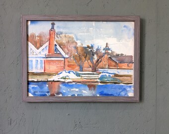 Puede incluir: Una pintura al agua enmarcada que representa un edificio de ladrillo con una chimenea y un árbol en primer plano. El edificio se refleja en una masa de agua en primer plano. La pintura está firmada "Jean Alexander" en la esquina inferior izquierda.
