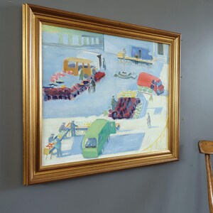 Pode incluir: Uma pintura a &oacute;leo emoldurada em ouro retrata uma movimentada cena de mercado ao ar livre. A obra apresenta ve&iacute;culos coloridos, incluindo um &ocirc;nibus amarelo, um caminh&atilde;o vermelho e uma van verde, rodeados por figuras e bancas de mercado. A pintura est&aacute; montada em uma parede cinza.