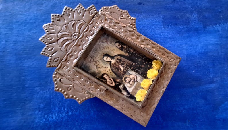 May include: A silver-toned metal frame with an ornate design, featuring a vintage photograph of a family inside. The frame is decorated with yellow paper flowers.
