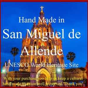 May include: Handcrafted in San Miguel de Allende, a UNESCO World Heritage Site. The image shows a brightly lit church at night with a blue sky and palm trees in the foreground. The text "Hand Made in San Miguel de Allende UNESCO World Heritage Site" is displayed on the image.