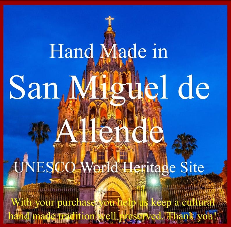 May include: Handcrafted in San Miguel de Allende, a UNESCO World Heritage Site. The image shows a brightly lit church at night with a blue sky and palm trees in the foreground. The text "Hand Made in San Miguel de Allende UNESCO World Heritage Site" is displayed on the image.
