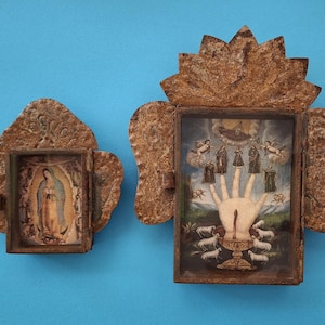 May include: Two antique religious shadow boxes with detailed artwork. One features an image of the Virgin Mary, the other a hand with figures and sheep. Both are framed in ornate, textured, brown metal.